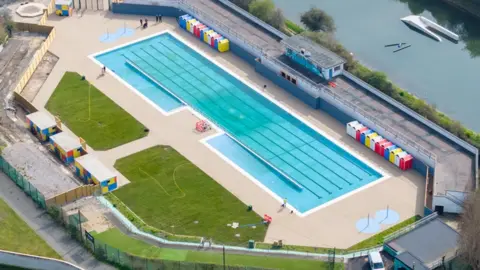 Portsmouth City Council An aerial view of the modernised lido, showing green leisure spaces next to the pool and within the lido perimeter. The image also shows the lido's location next to a body of water.