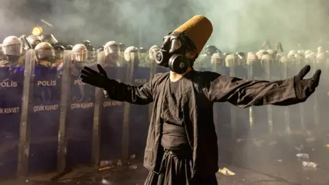 A protester wearing a whirling dervish costume performs in front of Turkish riot police barricades as he tries to march to Taksim Square from the Istanbul Municipality headquarters during a protest against the detention of Istanbul Mayor Ekrem Imamoglu in Istanbul, Turkey, 23 March 2025.