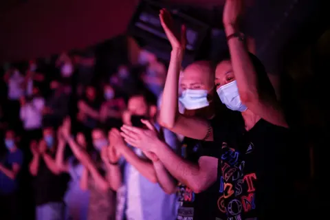 Henry Nicholls / Reuters People in masks applaud