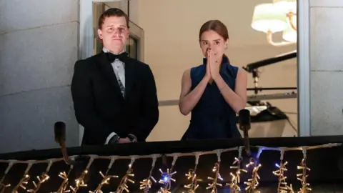 EPA A man and woman standing on a balcony covered in fairy lights, looking a bit emotional.