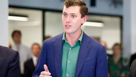 Flock founder and chief executive Garrett Langley wearing a blue suit jacket and green shirt