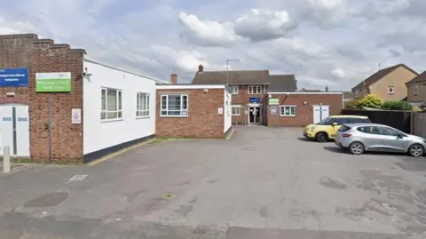 General view of the outside of Whittlesey Community and Youth Centre, a single story building with two cars in the car park.