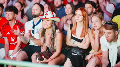 PA Media England fans on the edge of their seats watching the match on a big screen.