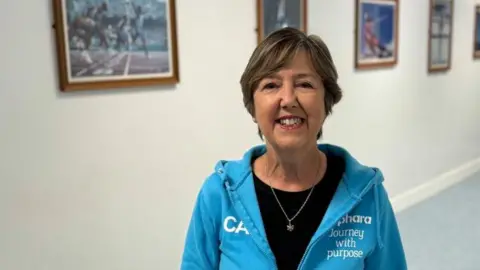 a lady with short blonde hair wearing branded blue hoodie