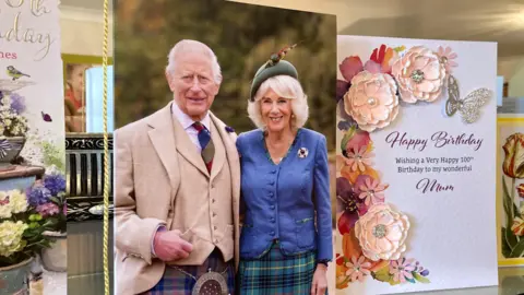 Birthday cards are displayed on a table. One of the cards shows King Charles and the Queen. 