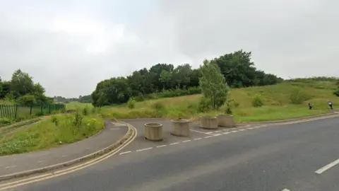 LDRS Land earmarked for development, with grass, trees and four bollards blocking a road 