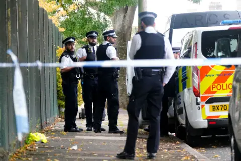 PA Officers standing behind police cordon at the scene of the fatal stabbing in Enfield, London
