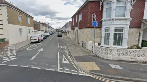 A Google street image view of Wadham Road from one end. The road contains rows of terrace houses with cars parked on both sides.