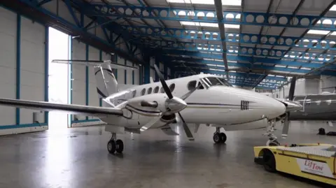 A white jet is visible inside a large hangar at Jersey airport.