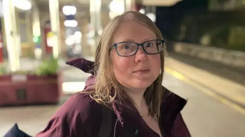 Woman with shoulder-length hair on a railway station platform