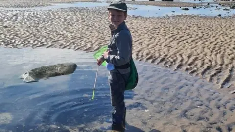 Dale Greetham Riley stands in a large pool on the beach