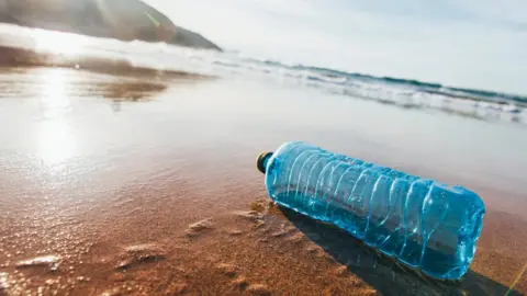 Getty Images A single discarded plastic water bottle on a sandy beach