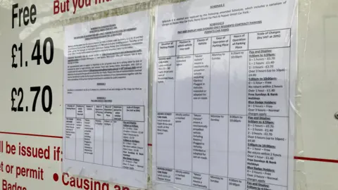 A sign in the car park with signs saying the new proposed parking charges