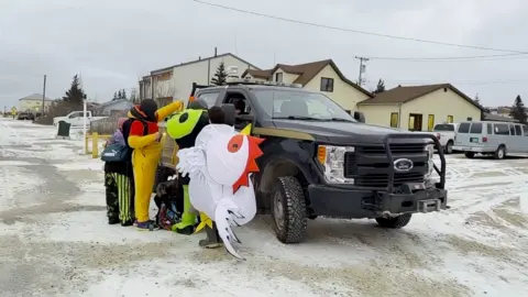 Annie Edwards Children in Halloween fancy dress speaking with polar bear alert rangers, who are guarding the town