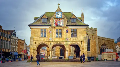 Peterborough's Cathedral Square - there are people wandering around the Old Market Hall.