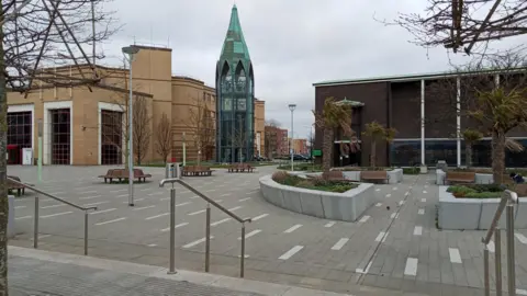 Owen Ward/BBC A general view of St Martin's Square in Basildon. It is a large paved area with benches and planters. There is a glass tower in the middle, a dark building to the right and the large cream council offices to the left.