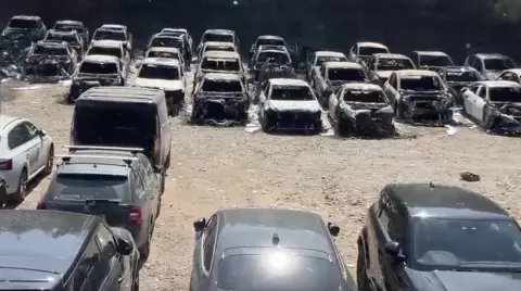 BBC A row of burned-out cars in front of cars unaffected by a fire