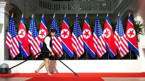 Reuters Worker vacuums spot where President Trump and Kim are expected to shake hands