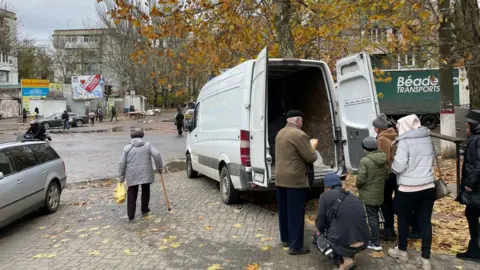 AFP In a picture of "cause and effect", bread is handed out under pro-Moscow billboards which read "Together with Russia".