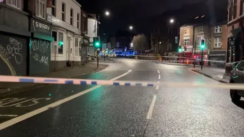 BBC/Oli Constable A police cordon on a residential street at night.