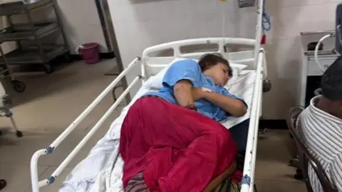Nic North A girl lies in a hospital bed