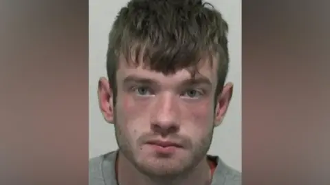 Mugshot of Wilkinson. He has short stubble and short thick dark hair.