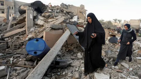 Reuters Palestinians inspect the site of an Israeli strike on a house in Deir al-Balah, central Gaza (15 January 2025)