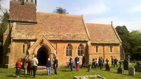 Mark Taylor The exterior of an historic church showing people in the graveyard