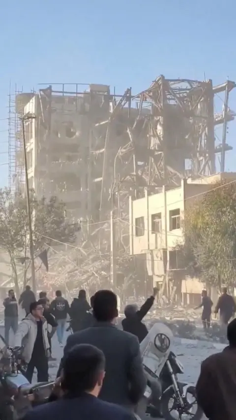 Social Media/via REUTERS Screengrab of video showing people standing near the destroyed building of Iran's Assembly of Experts, in Qom, central Iran (3 March 2026)