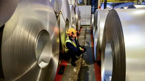 PA A worker inspecting rolls of steel