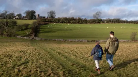 Getty Images A boy and a man walk on a path through a field in Somerset