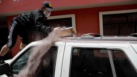 EPA A man cleans ash from the Sangay volcano off his vehicle in the town of Alausi, in the province of Chimborazo, Ecuador, 20 September 2020