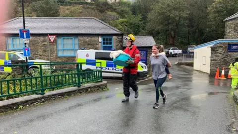 Civil defence volunteer helps a mother and child