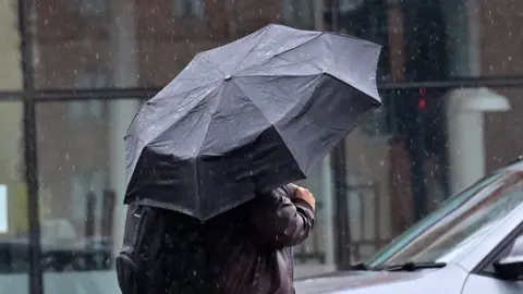 Pacemaker Press A Man using an umbrella in the rain