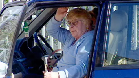A photo of Haney from her later days as she tries to get oiut of a car. She has a walking stick and looks frailer than earlier photos