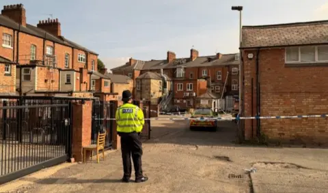 A police officer stands before police cordon