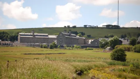 Dartmoor Prison surrounded by green fields on a sunny day.