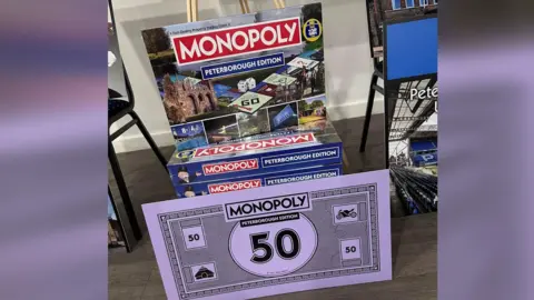 Blue and red Boxes of the board game with purple Monopoly 50 note in front 