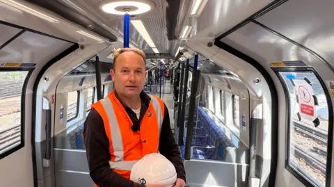 A man in hi-vis stands in the train