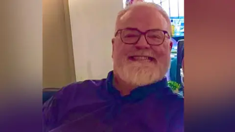 Alan Gregory Alan in a dark coloured polo shirt smiling at the camera.