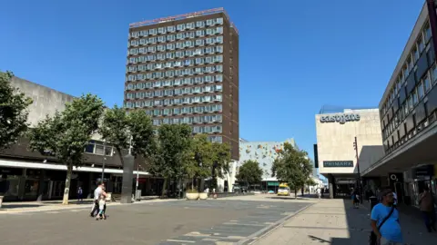 Owen Ward/BBC A general view of Basildon town centre. There are parades of shops and a large brown tower block.