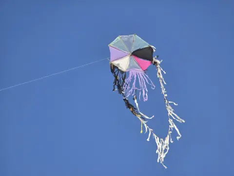 A kite flies against a cloudless sky