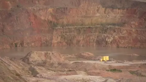 Water can be seen surrounded by red rocks at the mine.