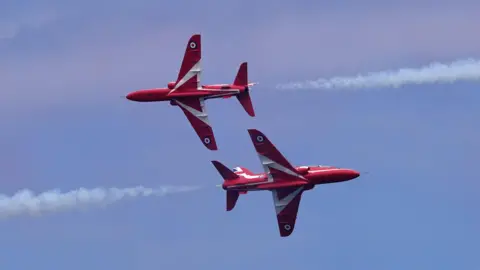 Two Red Arrows jets passing within feet of each other, flying in opposite directions