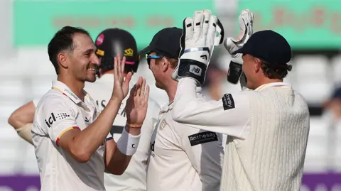 Essex's Zaman Akhter celebrates with team mates after taking the wicket of Surrey's Matthew Fisher at Chelmsford