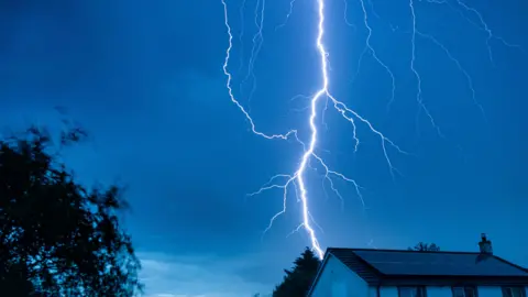 Cumbrian stargazer A bold white lightning strike forks across the night sky directly over the roof of a house in Haile.