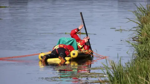 Shaun Whitmore/BBC Two search and rescue members scouring the water on a small boat