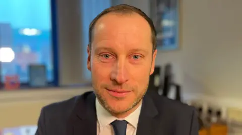 Nottinghamshire Police DI McDonagh is wearing a dark suit and tie