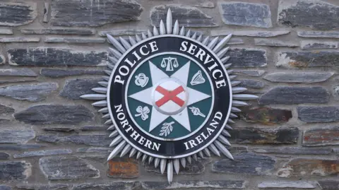 A PSNI logo on a brick wall
