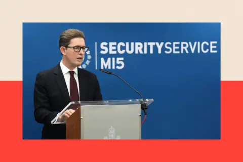 PA Ken McCallum standing at a podium